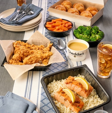 Get a family bundle at Cheddar's. Get sides of broccoli, carrots, croissants, and queso with your choice of grilled salmon or chicken tenders.