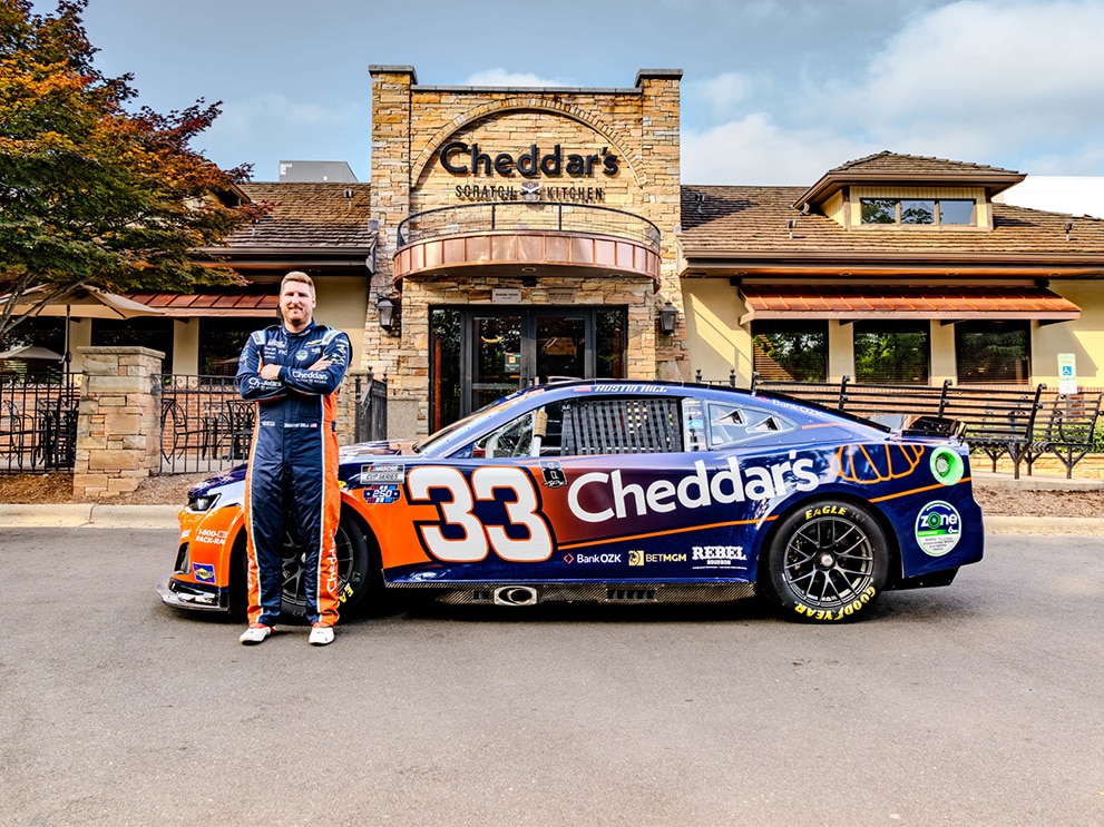 Austin Hill standing beside the No. 33 Cheddar's Chevy race car